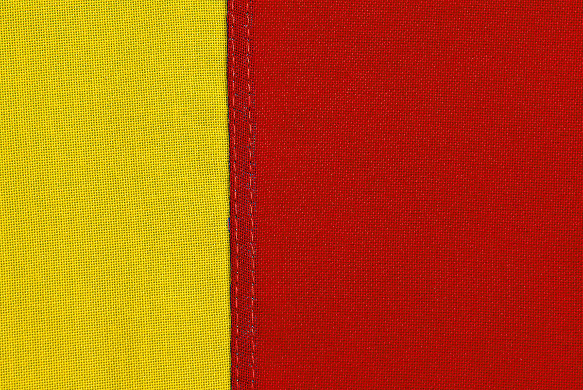 Närbild på en skånsk flagga där man ser textilens struktur, sömmen och tråden.