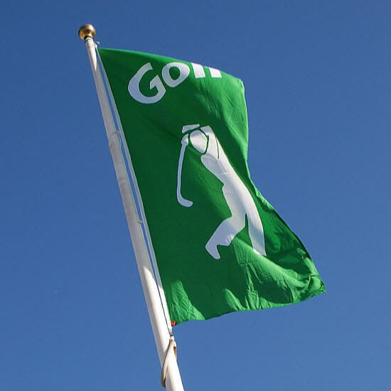 grön golf flagga som vinglar på en flaggstång med blå bakgrund