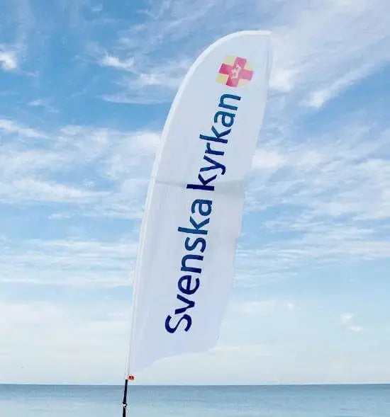 Beachflagga med svenskakyrkans logga på 
