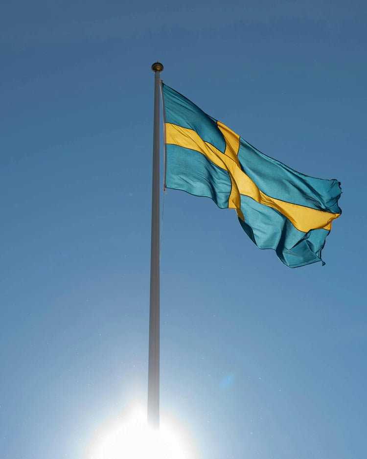 Flaggstång med sverigeflagga med blå himmel som bakgrund